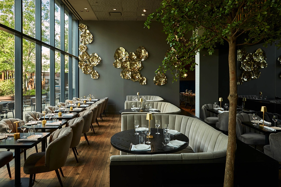 Elegant restaurant interior featuring plush seating, golden wall art, and large windows inviting natural light.