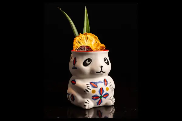 A decorative ceramic rabbit planter with colorful floral designs, featuring vibrant green leaves and a bright yellow flower on top.
